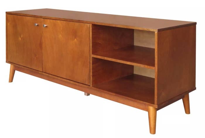 A mid-century modern wooden TV stand with two open shelves on the right and a cabinet on the left