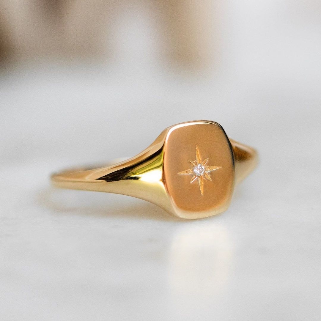 a square chunky gold ring with a star in the center with a stone in the middle