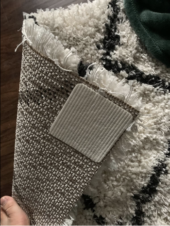 a reviewer photo of the rug grippers stuck to the back of a rug