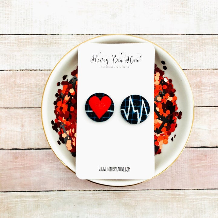 two button earrings with a red heart on one and the lines similar to those on an EKG scan on the other