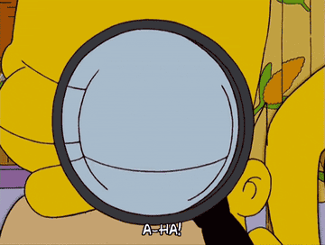 Homer Simpson using a magnifying glass to inspect something tiny
