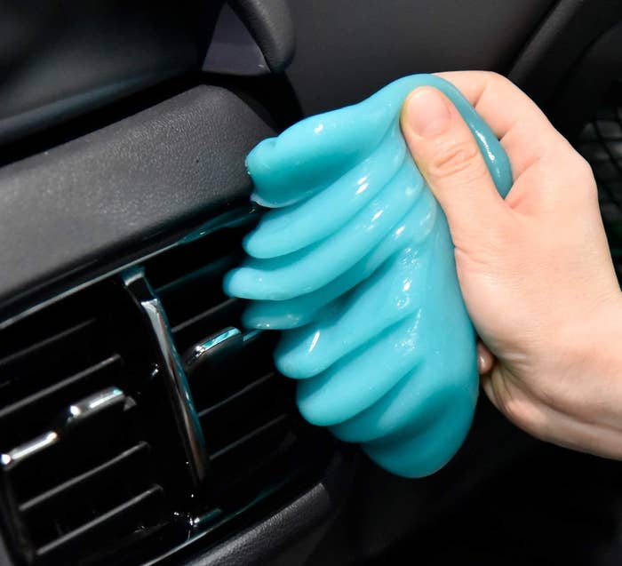 A person using the cleaning gel on a vent inside of a car