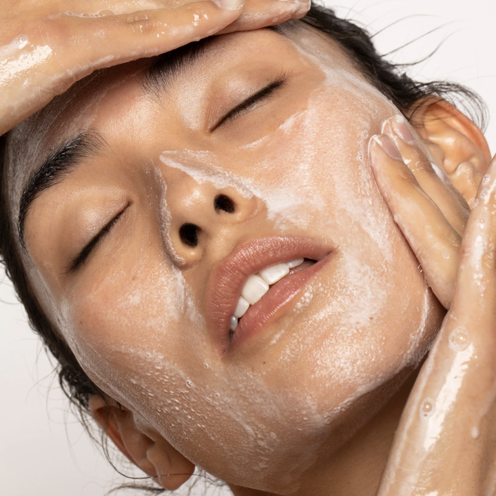 person lathering skin with cleanser