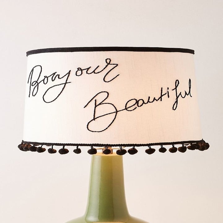 white lampshade with "bonjour beautiful" written with black thread 