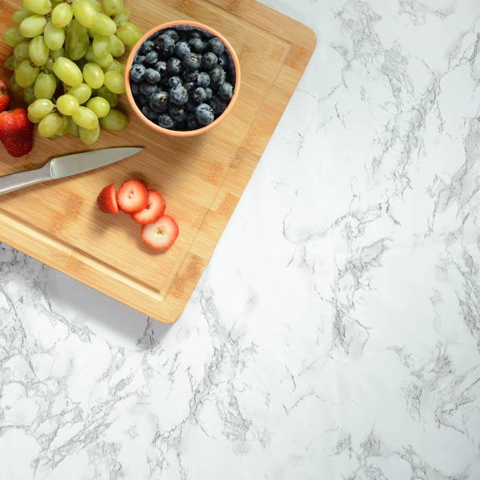 counter with marble contact paper on it and a cutting board on top