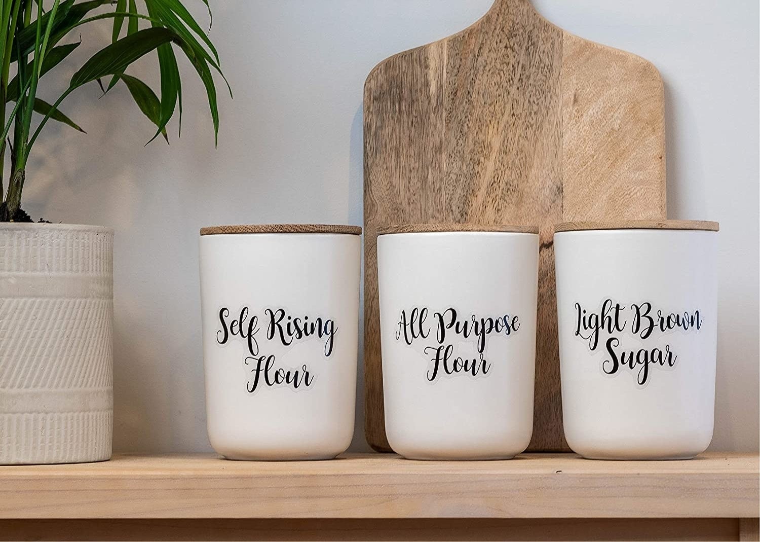 A trio of ceramic food containers labelled with dry baked good ingredients