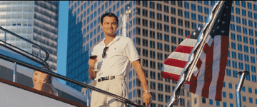 Leonardo DiCaprio raising a glass on a yacht with an American flag on it