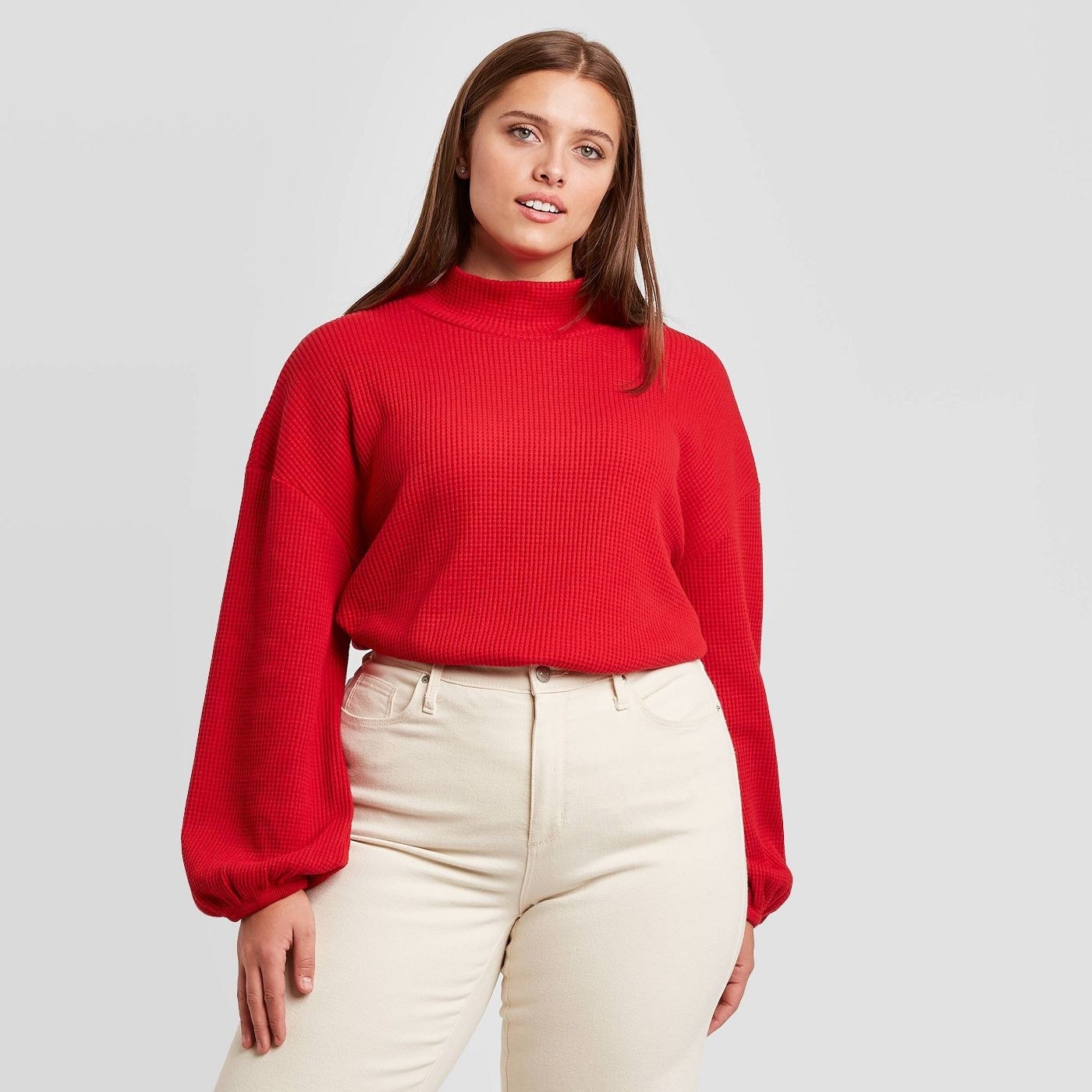 A model wearing a red mock turtleneck sweater with puffy sleeves