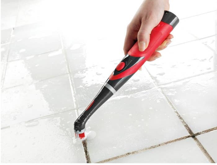 person using a rubbermaid power scrubber to clean dirty grout