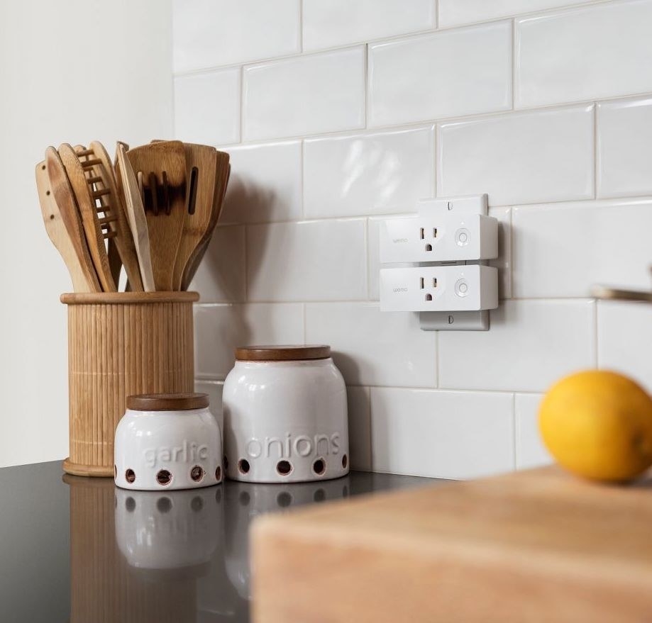 two white smart plugs in a kitchen outlet