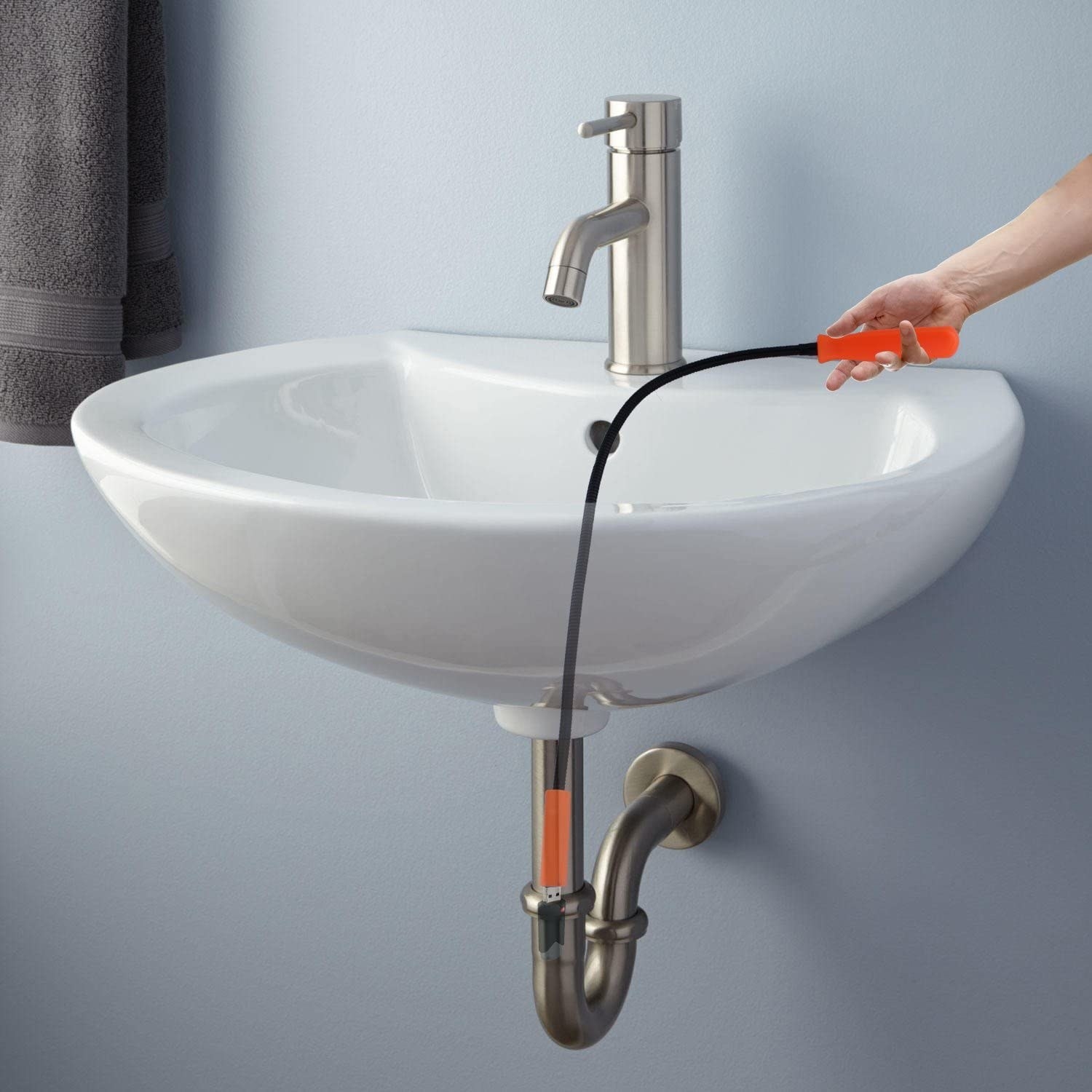 A person using the magnetic tool to retrieve something from a sink drain
