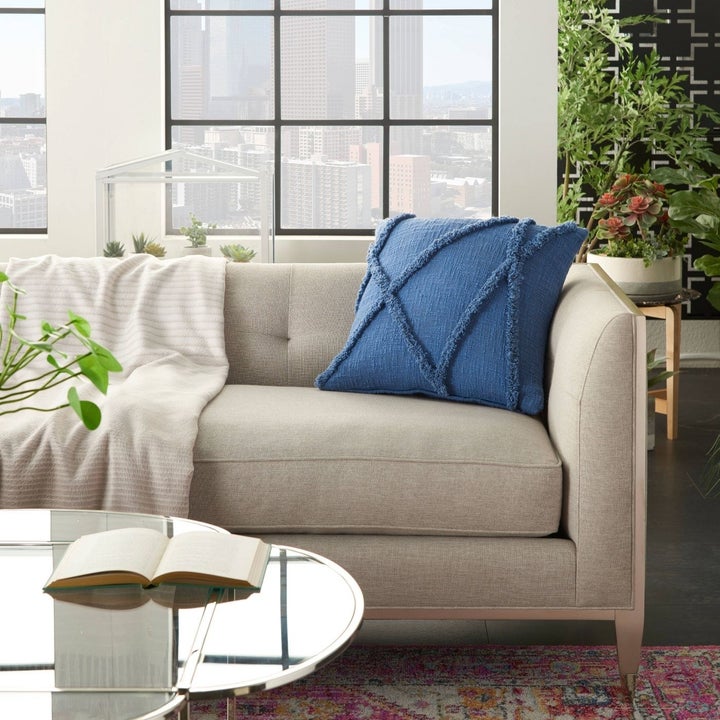 blue tufted throw pillow on a beige couch in a living room