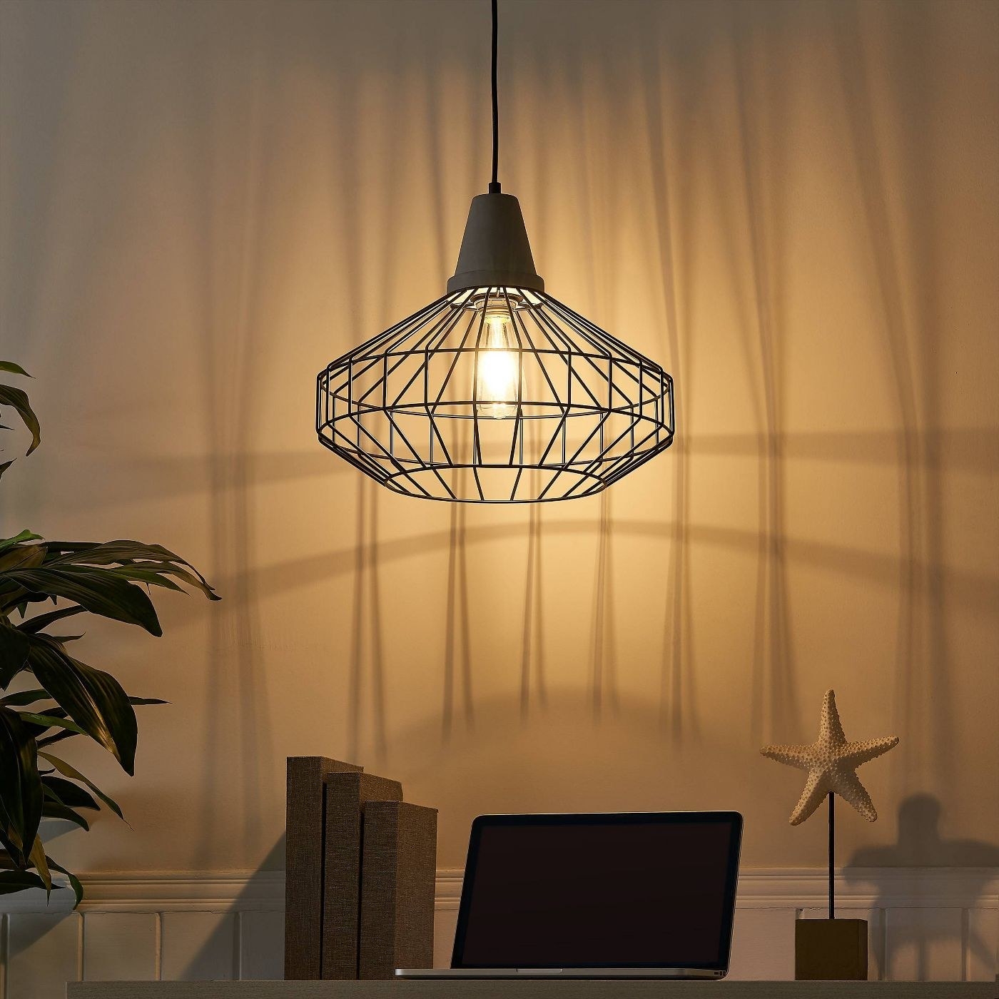 cage pendant lamp lit up over a desk