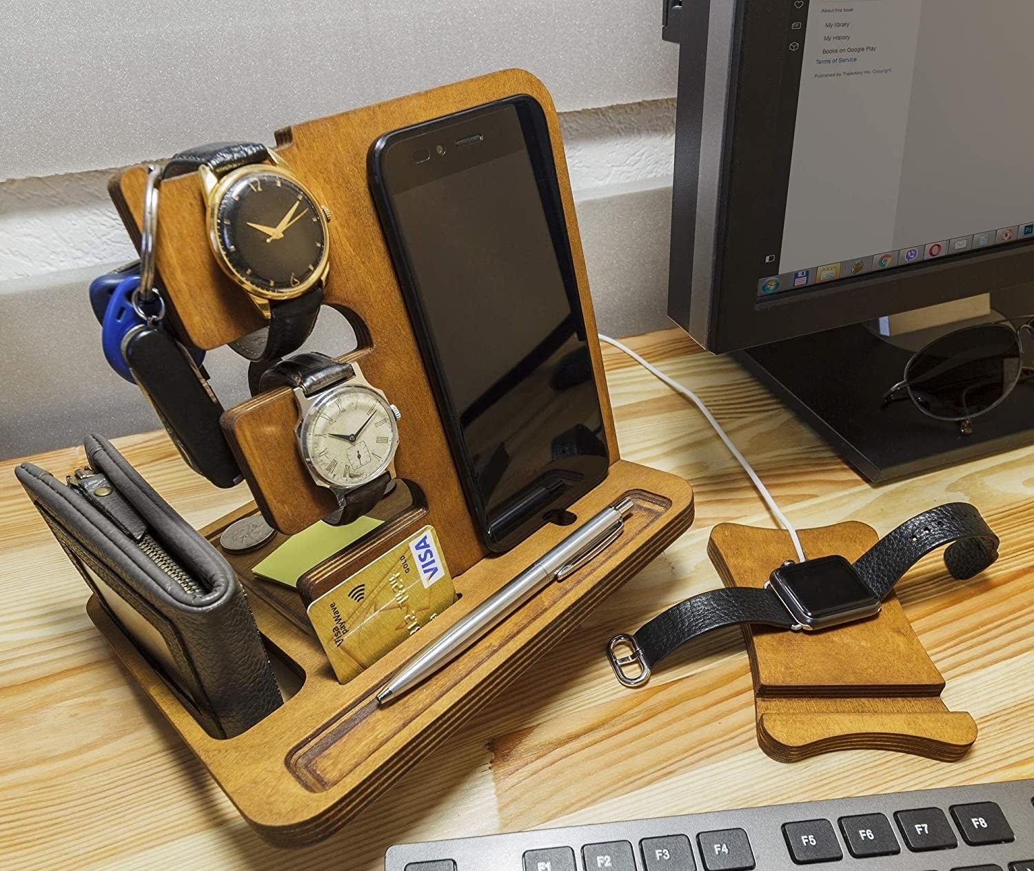 The docking station with a phone, wallet, watches, pen and credit card organized 