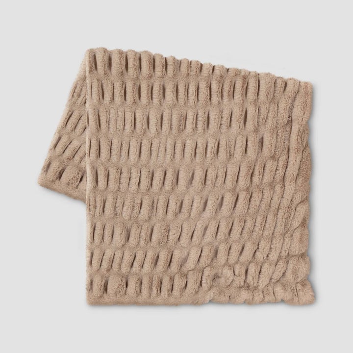 a beige faux fur blanket with ruched details