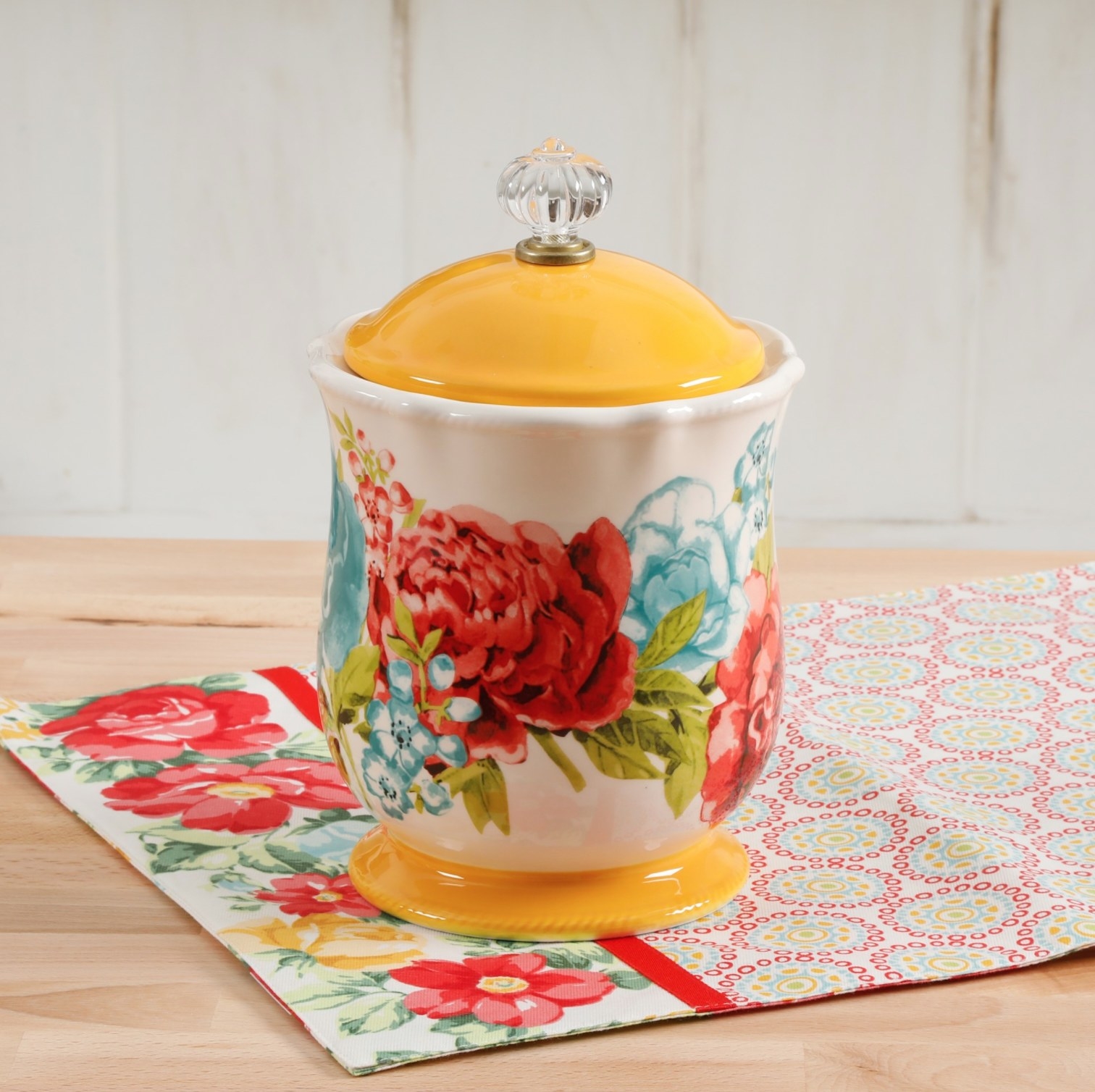 The canister with red and blue flowers and a yellow top