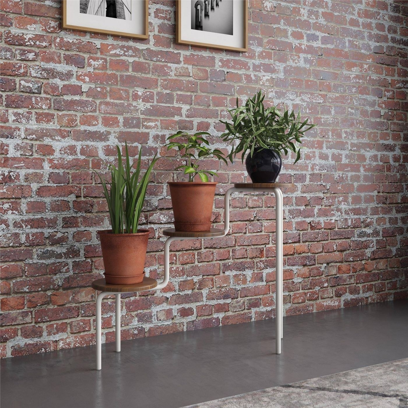 three-tier plant stand in front of an exposed brick wall