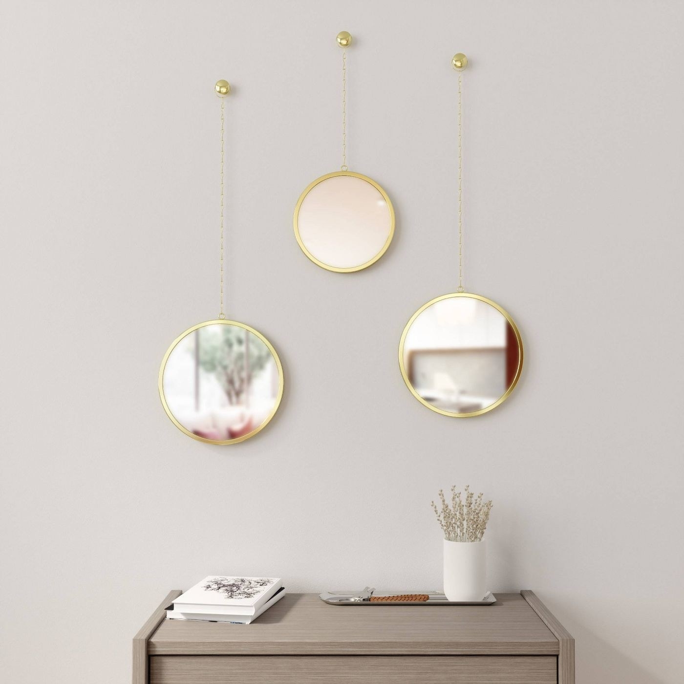 three round decorative mirrors hanging up on a wall over a dresser