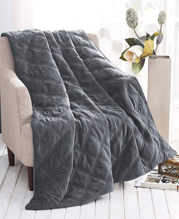 The weighted blanket draped over a plush chair 