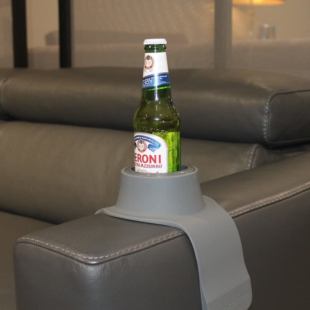 A large coaster draped over the armrest of a sofa holding a beer bottle