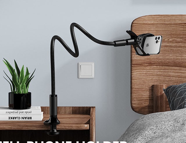 The flexible phone stand clipped onto a bedside table