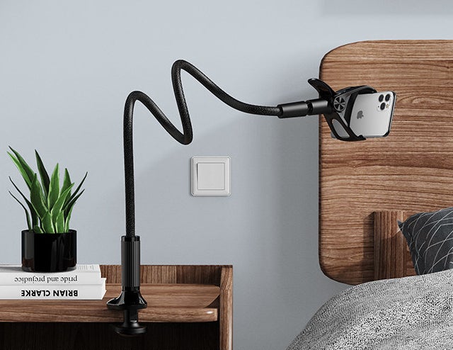 The flexible phone stand clipped onto a bedside table