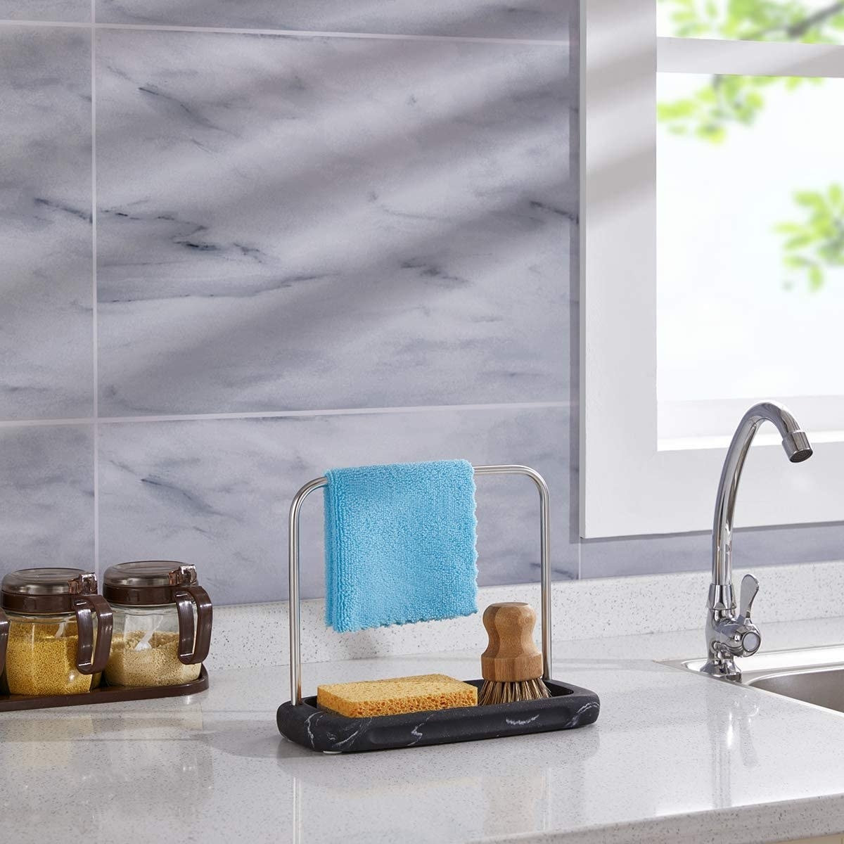 The caddy with a cloth hanging over it above a sponge and scrub on a counter