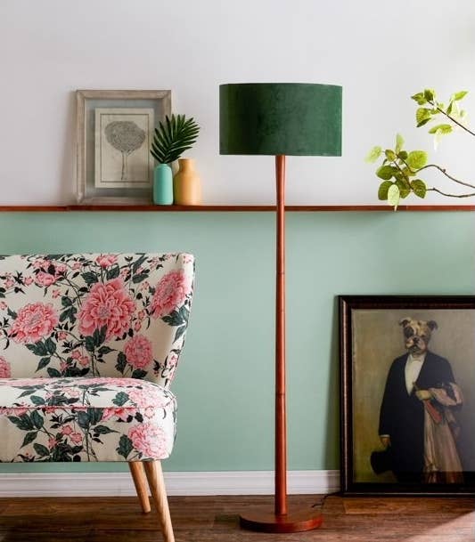 The lamp, which has a circular wooden base and wooden pole, both in a cherry wood finish, topped with a green velvet circular shade