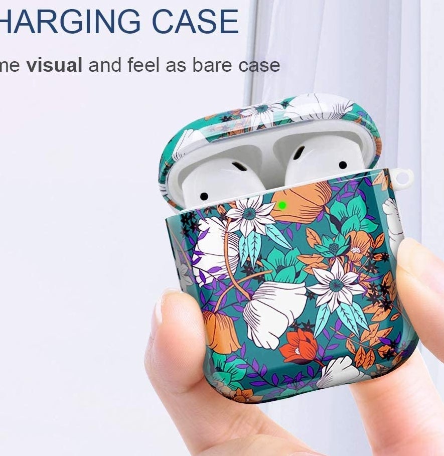 A person holding up a pair of AirPods that are covered in a floral-print case