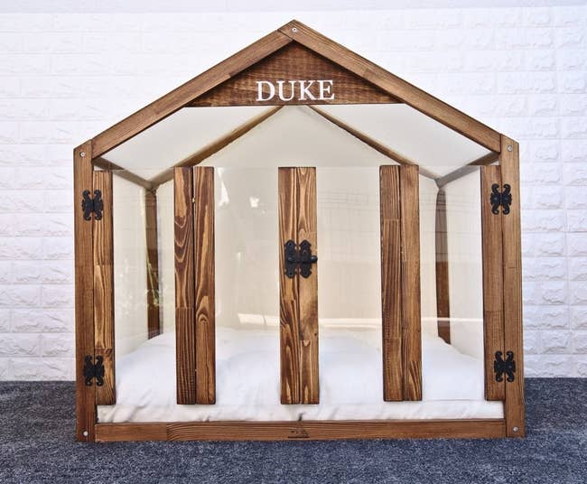 house-shaped dog house with plush bedding and glass door