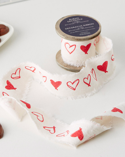 A roll of fabric ribbon covered in hand-drawn illustrations of hearts