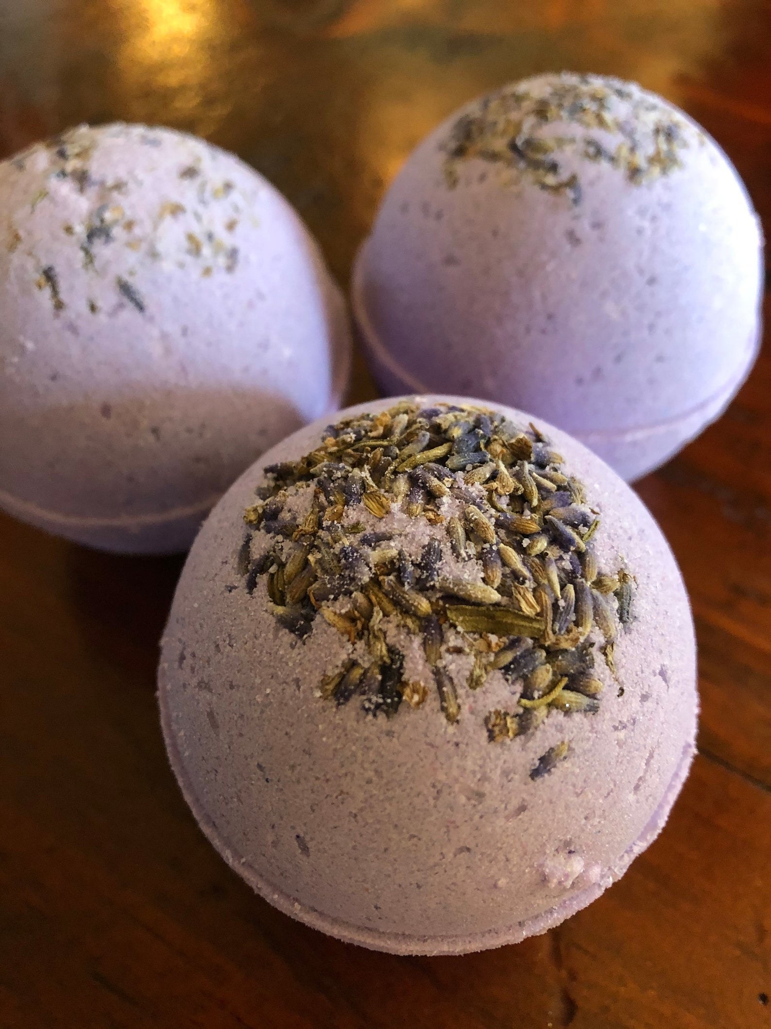 three lavender bath bombs with buds in the top