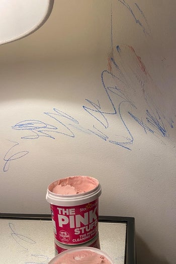 A reviewer's before photo which shows a white wall covered in crayon scribbles
