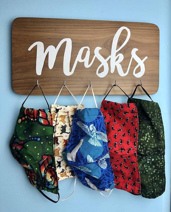 the face mask wall mounted rack with a mask hanging from each of its five hooks