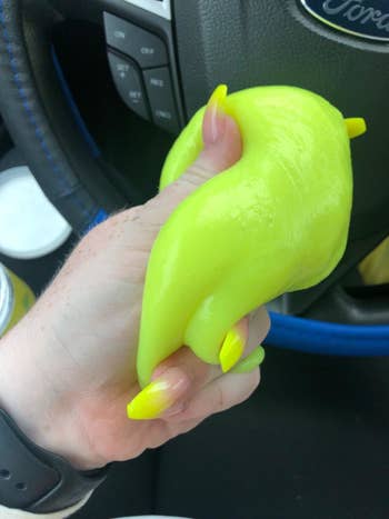 A reviewer holding the neon yellow cleaning gel