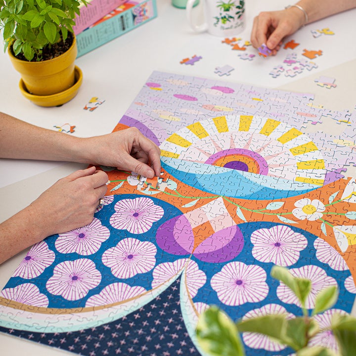 Hands put together puzzle pieces on same flower-themed puzzle