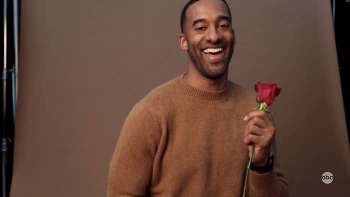 Matt James laughing while holding a rose