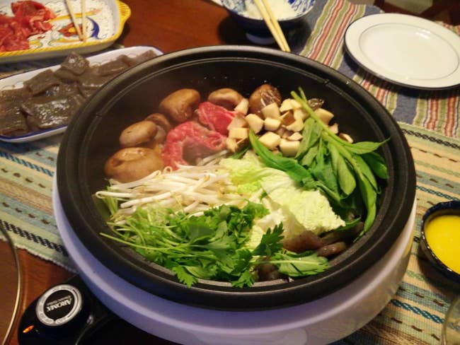 reviewer pic of the white and black pot with assorted veggies, potatoes, and meat inside on a table