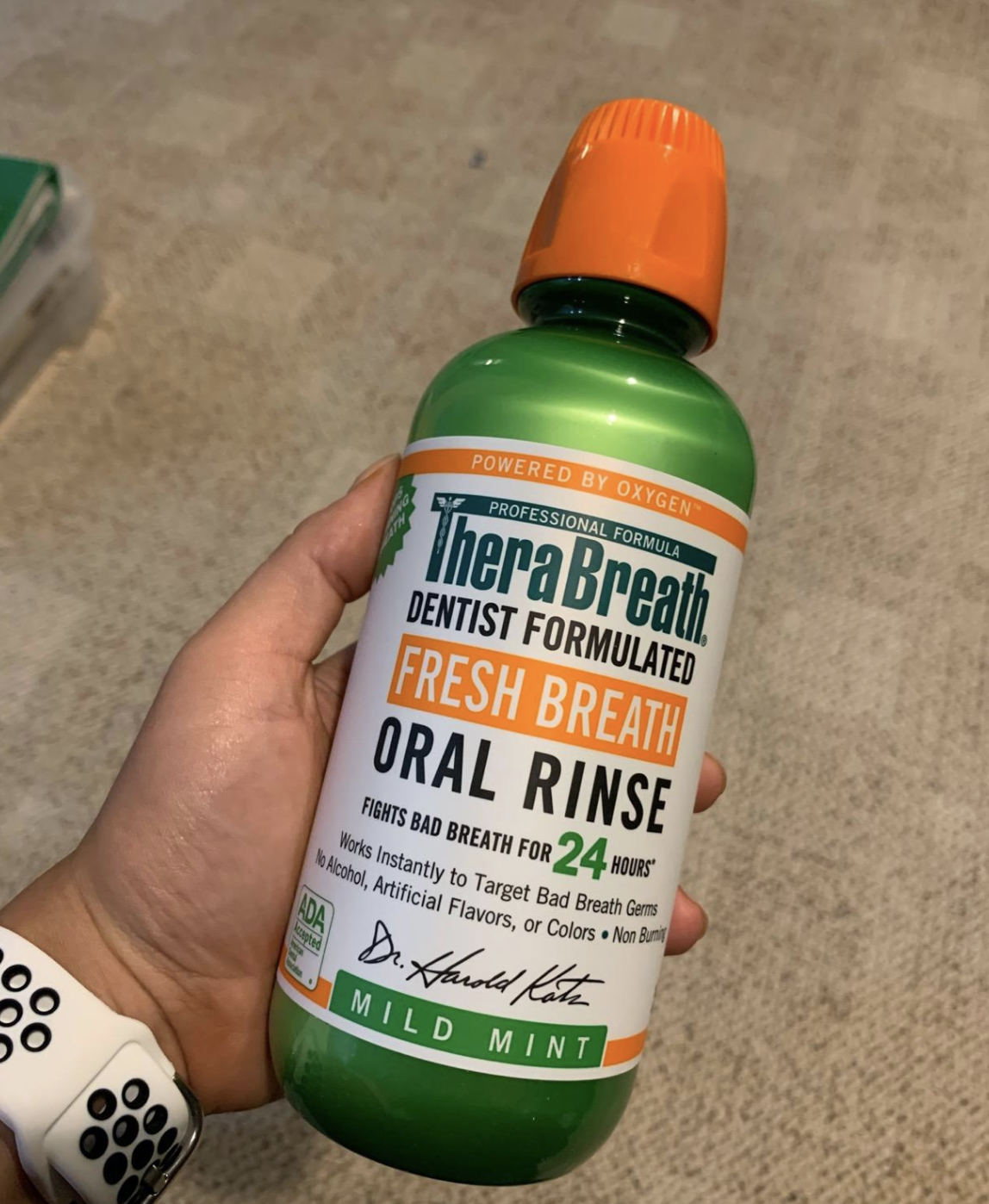 reviewer holding bottle of mild mint Therabreath oral rinse