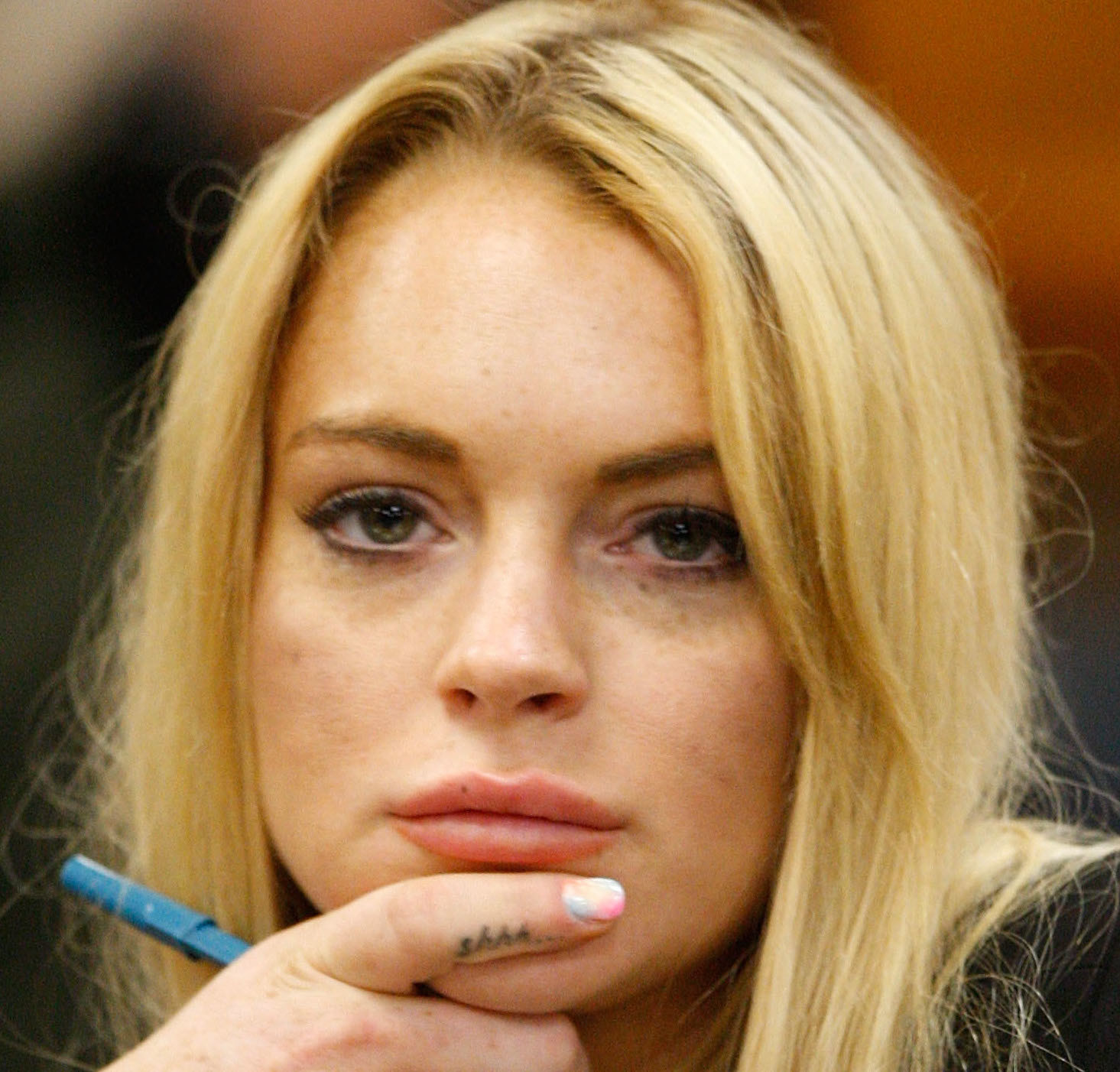 Lindsay with her hand touching her chin and showing the tat on her pointy finger