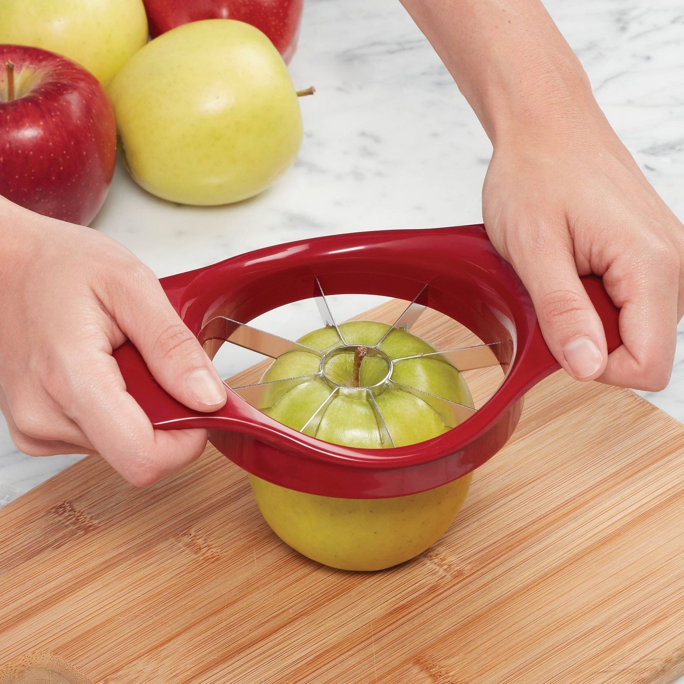 Hands using the tool to slice an apple