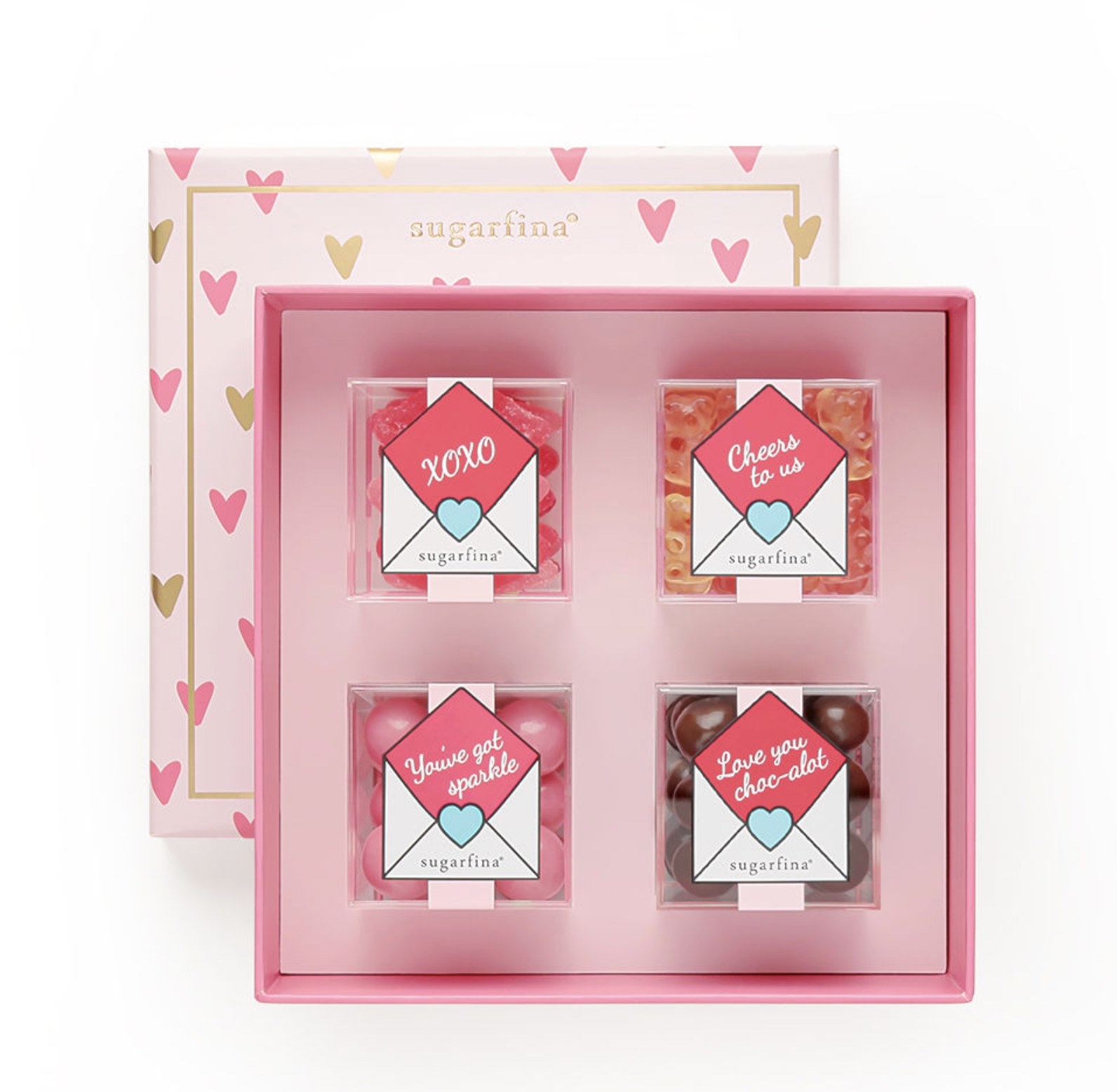 Four lucite boxes of candies with love letter stickers in a pink gift box