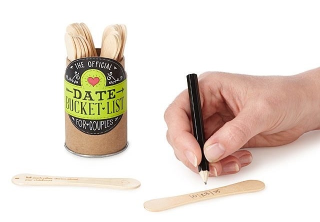 a model writing on a popsicle stick next to a tin filled with popsicle sticks