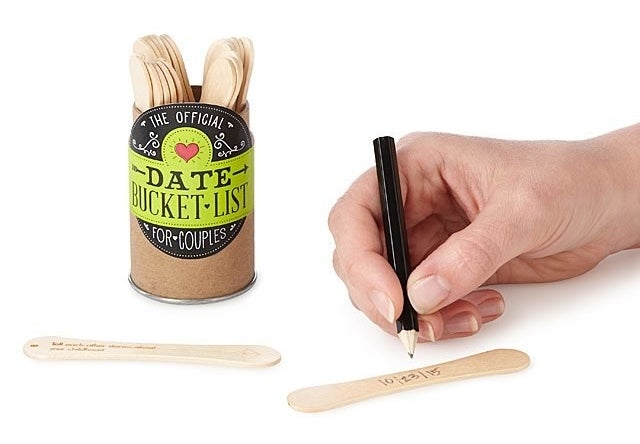 a model writing on a popsicle stick next to a tin filled with popsicle sticks