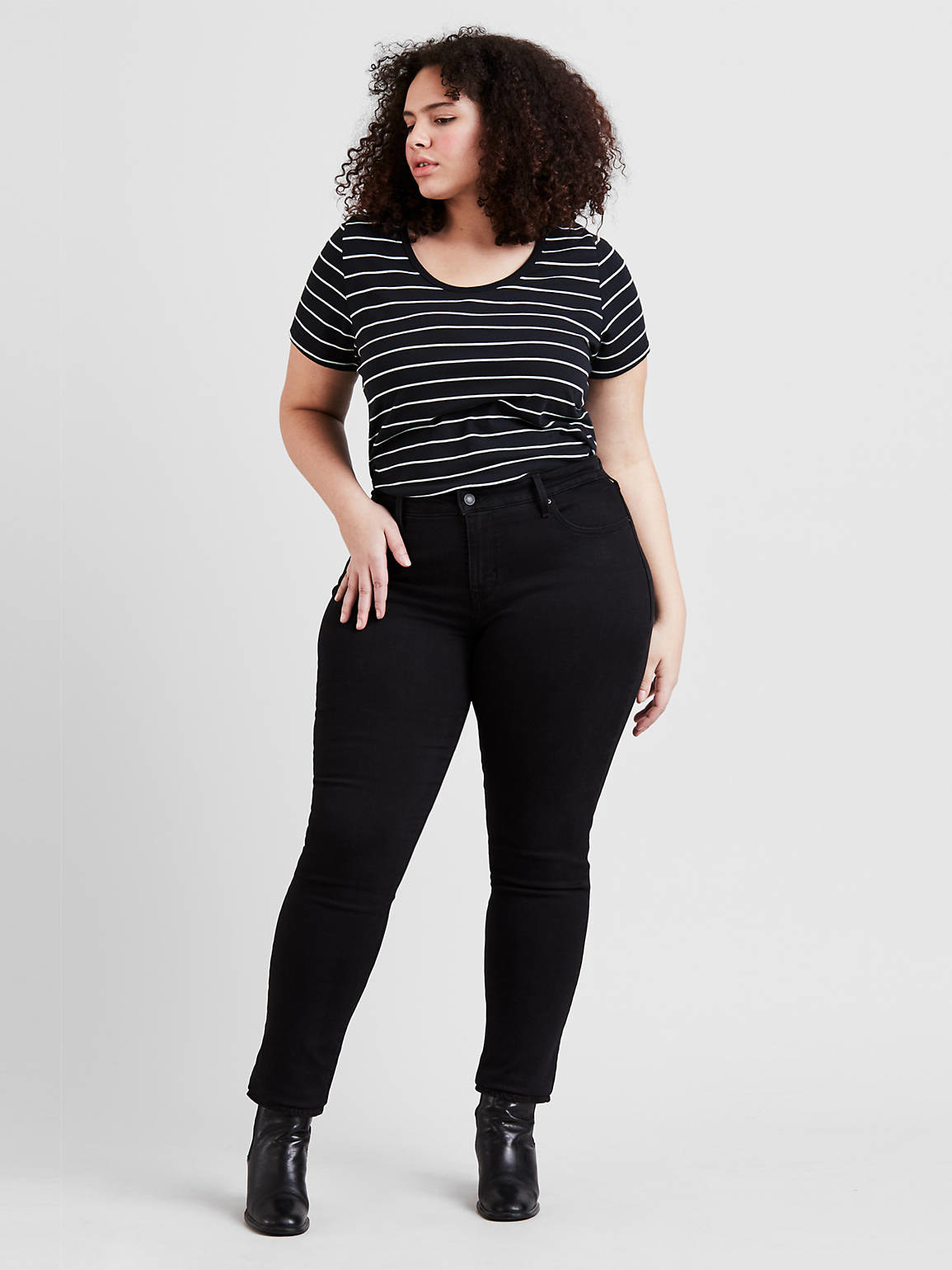 a model wearing the jeans in black with a striped shirt and booties
