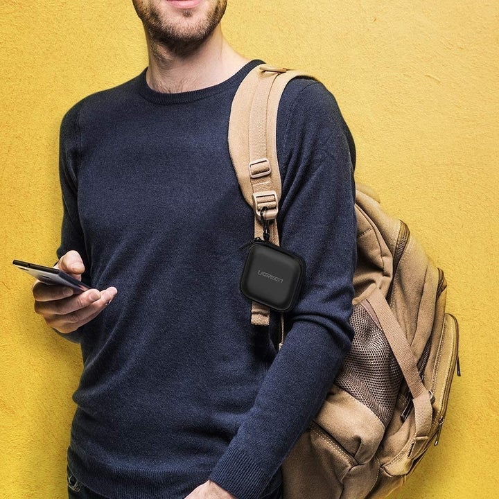 Model with zipped up case attached to backpack strap