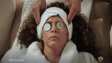 Woman with cucumbers on face getting a head massage