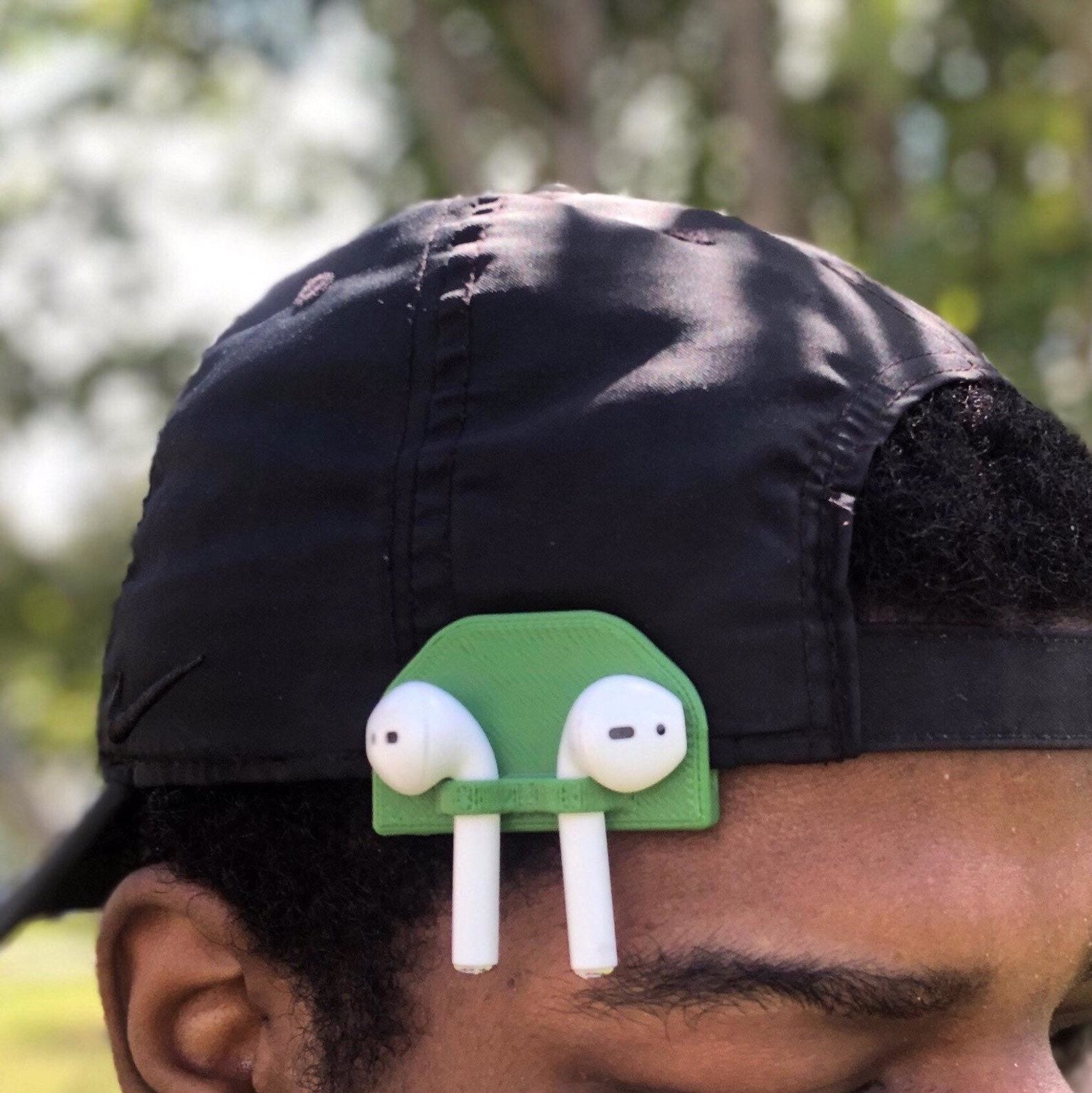 Model wearing green AirPod holder clipped onto hat