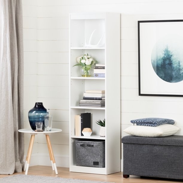 The bookcase, which is white and has five shelves