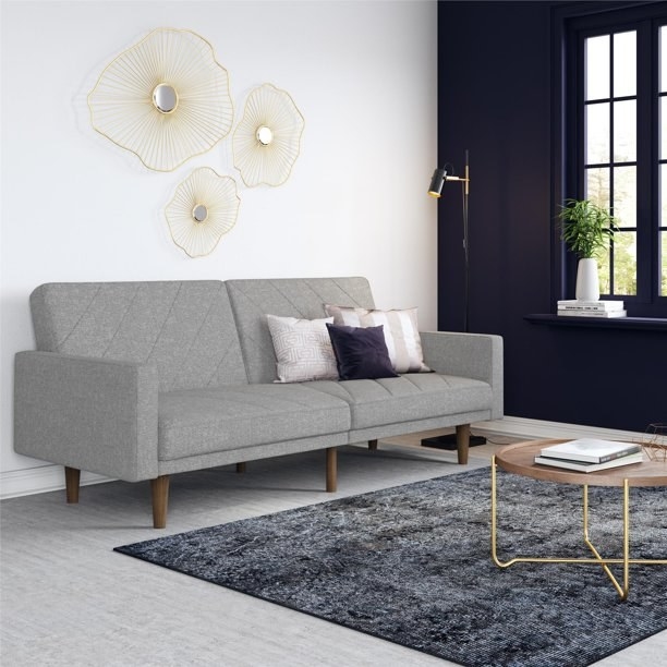 The couch in gray, with six small wooden peg legs and two raised arms at either end